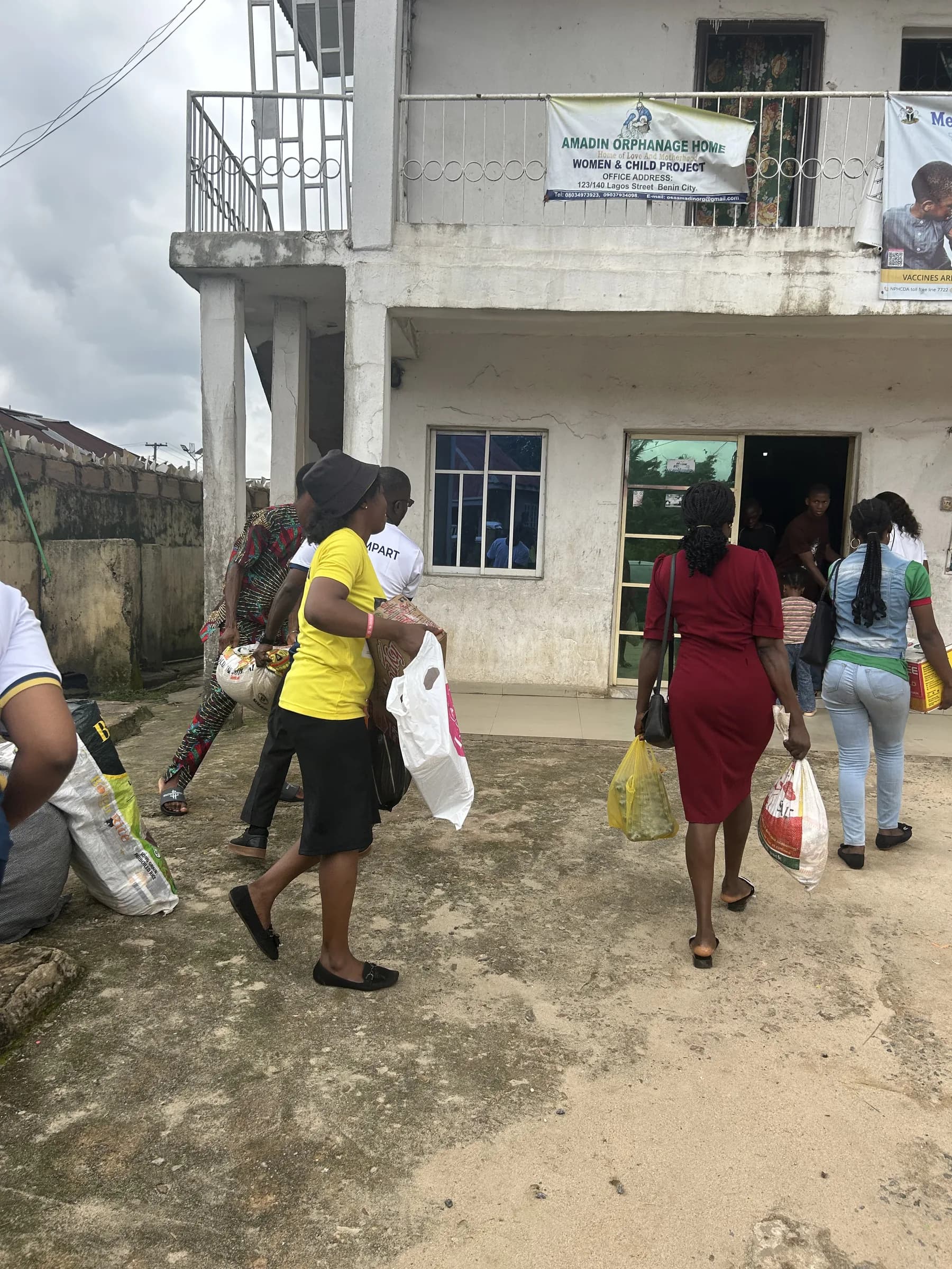 Volunteers walking in to the orphanage carrying bags of donations.