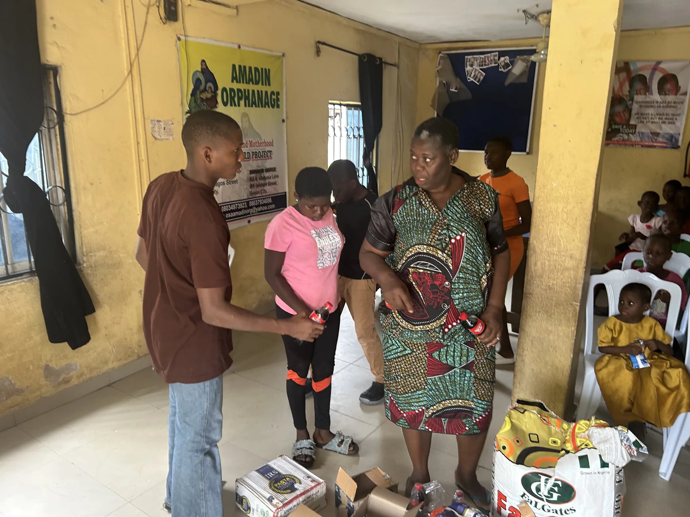 Volunteers handing donated items to children during the Amadin Orphanage outreach.