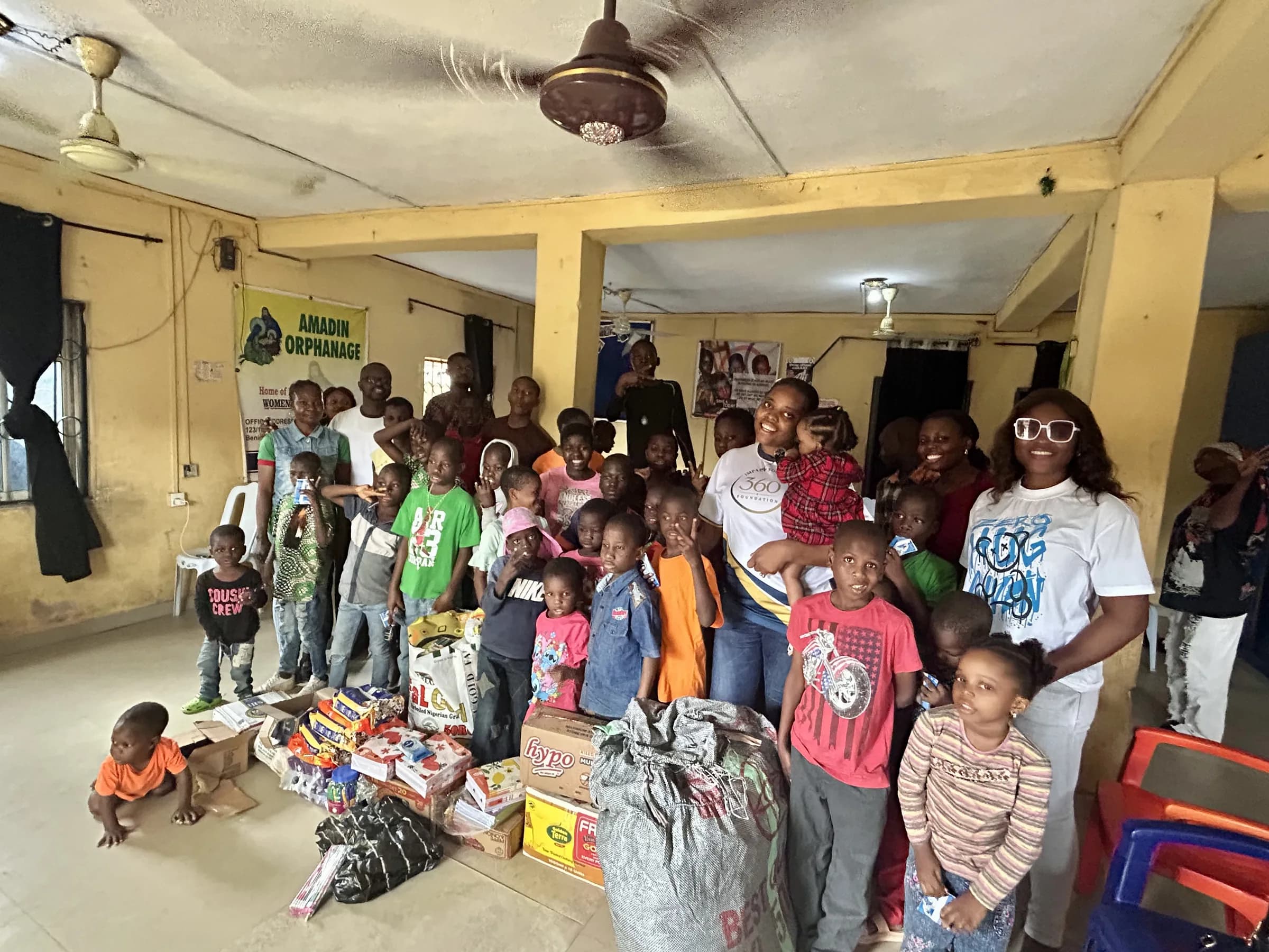 Children at Amadin Orphanage standing with volunteers and the delivered supplies.