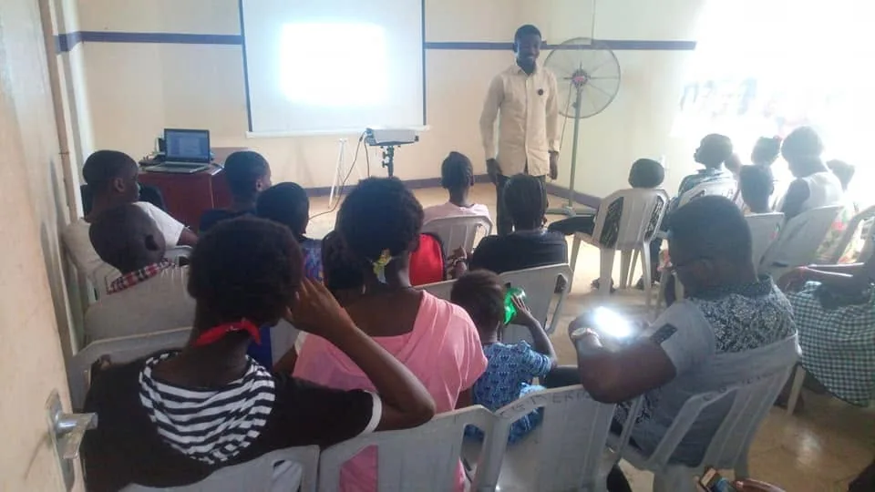 Young people seated together during a club session, with a facilitator leading from the front.